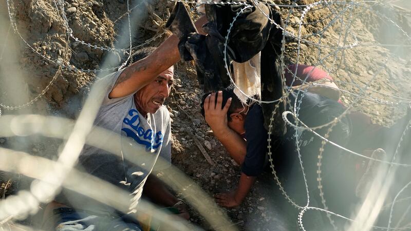 Migrantes que cruzaron el Río Bravo desde México a Estados Unidos pasan por debajo de un...