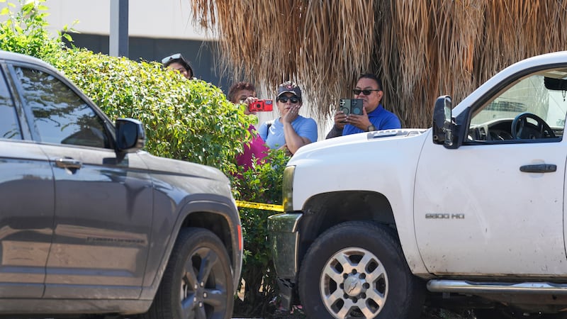 Varias personas observan mientras policías del condado Harris trabajan en el lugar cerca de...