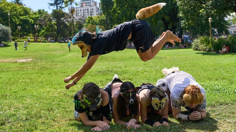 A youth jumps over other therians, people who say they identify as non-human animals, during a...