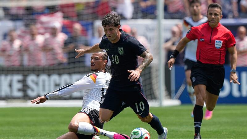 El atacante estadounidense Christian Pulisic (derecha) es derribado por el atacante alemán...