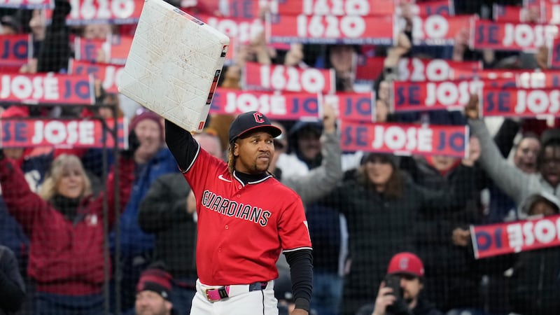Cleveland Guardians third baseman José Ramírez holds third base after being presented with the...