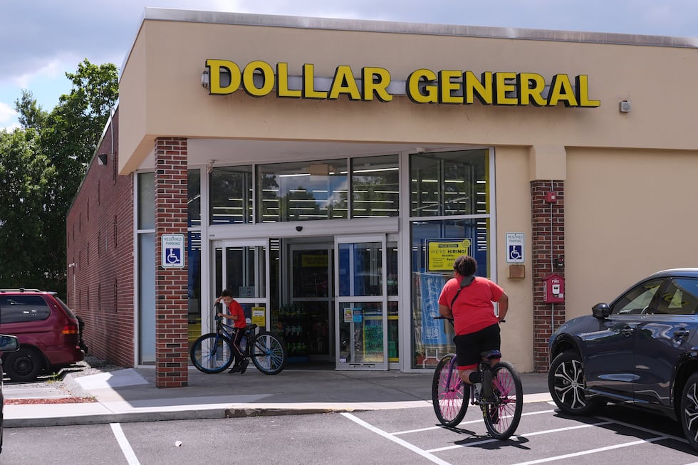 ARCHIVO - Unos niños van en bicicleta a la tienda Dollar General, el 21 de agosto de 2025, en...