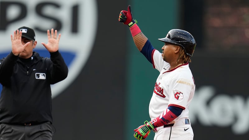 Cleveland Guardians' José Ramírez gestures to the dugout from second base after hitting a...