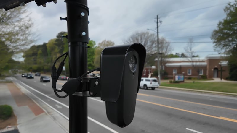 A Flock Safety camera positioned to capture license plates of traffic passing by.