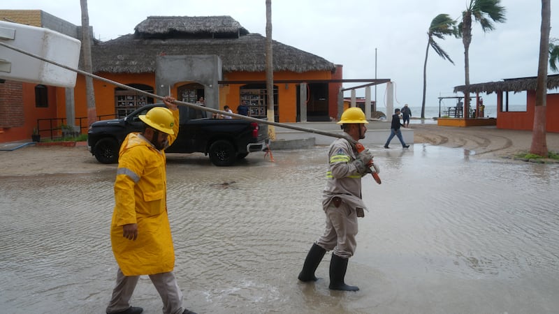 Trabajadores remolcan una embarcación a tierra mientras el huracán Polo se aproxima a Puerto...